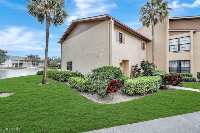 view of property exterior featuring a water view, a lawn, and stucco siding