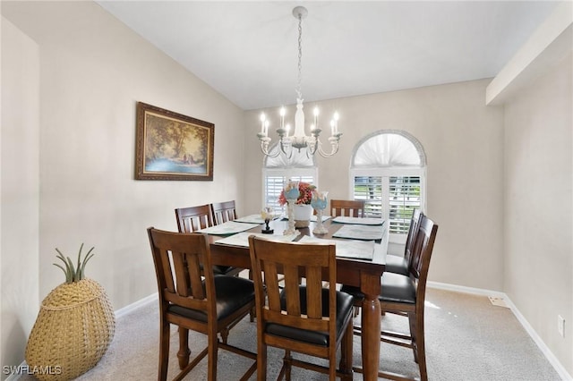 dining room featuring carpet, a notable chandelier, lofted ceiling, and baseboards