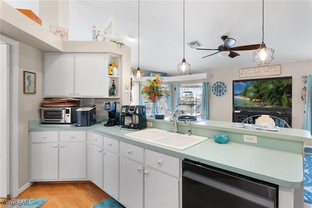 kitchen featuring dishwashing machine, a peninsula, a sink, light countertops, and open shelves