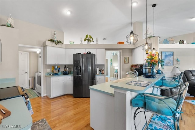 kitchen featuring a peninsula, a sink, black fridge with ice dispenser, white cabinets, and light countertops