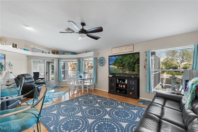 living room with ceiling fan, wood finished floors, visible vents, and lofted ceiling