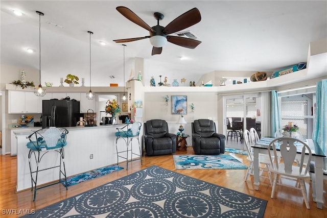 living room featuring vaulted ceiling, ceiling fan, light wood-type flooring, and visible vents