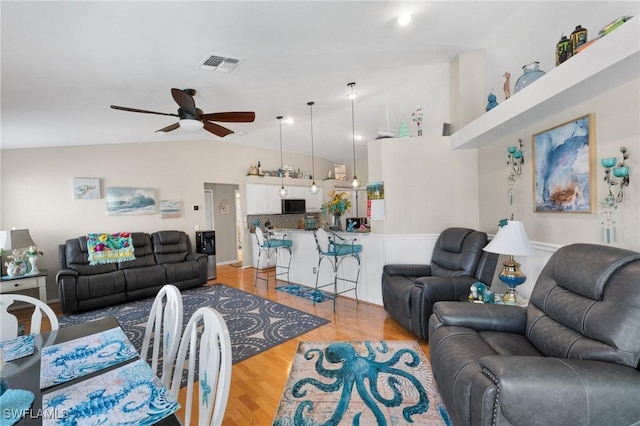 living area with visible vents, vaulted ceiling, light wood finished floors, and ceiling fan