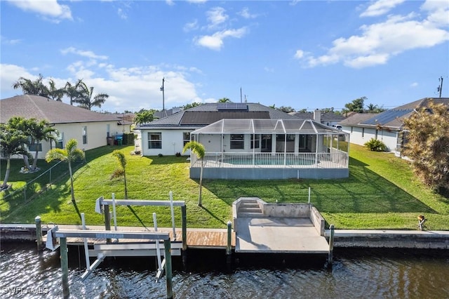 back of house with an outdoor pool, a water view, and a lawn