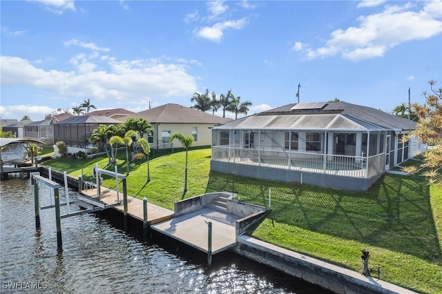 back of house featuring glass enclosure, boat lift, a water view, a yard, and a pool