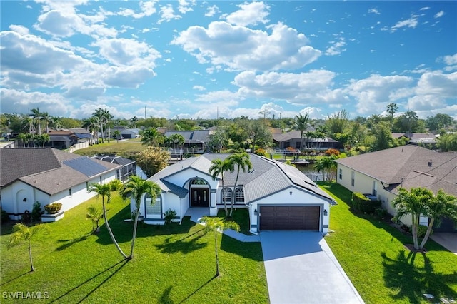 view of front of home featuring a garage, a residential view, driveway, and a front yard