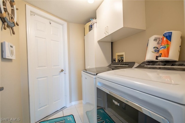 laundry room with light tile patterned floors, washing machine and dryer, cabinet space, and baseboards