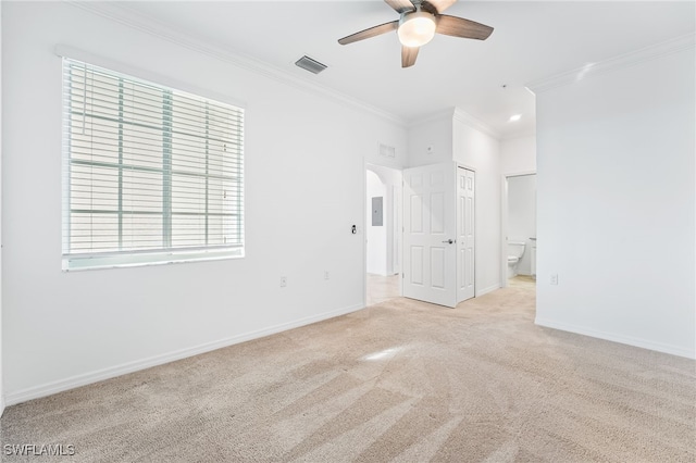 carpeted empty room with visible vents, ceiling fan, baseboards, ornamental molding, and arched walkways