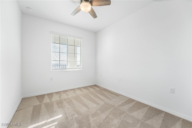 spare room featuring a ceiling fan, light colored carpet, and baseboards