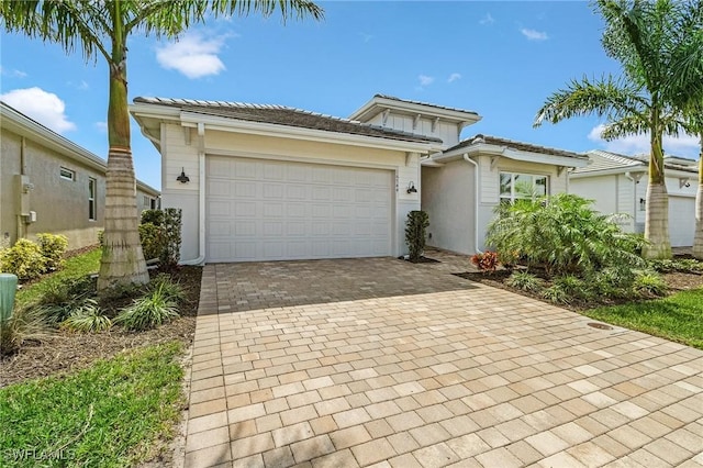 view of front of property featuring an attached garage, a tile roof, decorative driveway, and stucco siding