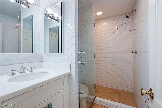 bathroom with toilet, vanity, a shower stall, and tile walls