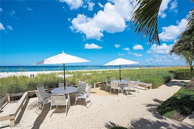 view of patio with a water view and a beach view