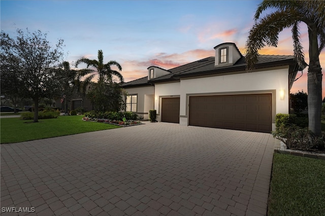 view of front of house featuring a garage, a front lawn, decorative driveway, and stucco siding