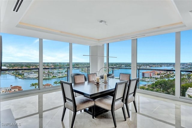 sunroom featuring a tray ceiling, a water view, and visible vents