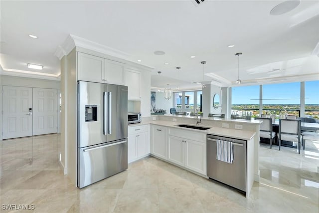 kitchen with stainless steel appliances, a peninsula, a sink, white cabinetry, and a tray ceiling