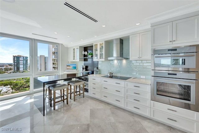 kitchen with black electric stovetop, stainless steel double oven, visible vents, decorative backsplash, and wall chimney exhaust hood