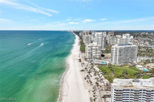 drone / aerial view featuring a water view, a city view, and a view of the beach