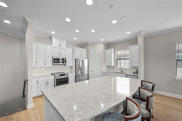 kitchen with a center island, tasteful backsplash, appliances with stainless steel finishes, white cabinets, and light wood-type flooring