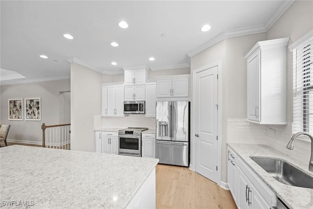 kitchen with light wood-type flooring, white cabinetry, appliances with stainless steel finishes, and a sink