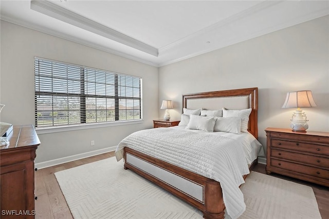 bedroom featuring crown molding, a raised ceiling, and wood finished floors