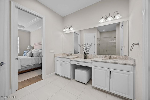 ensuite bathroom with double vanity, ornamental molding, a stall shower, a sink, and tile patterned floors