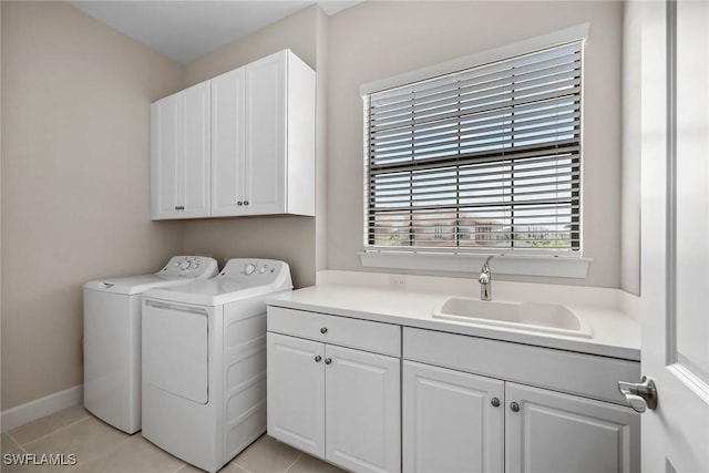 laundry area featuring light tile patterned floors, a sink, baseboards, cabinet space, and washing machine and clothes dryer