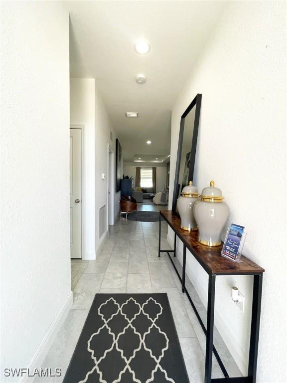 hallway featuring recessed lighting, visible vents, baseboards, and light tile patterned flooring