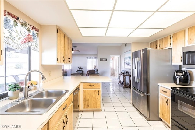 kitchen featuring appliances with stainless steel finishes, a peninsula, light countertops, a sink, and light tile patterned flooring