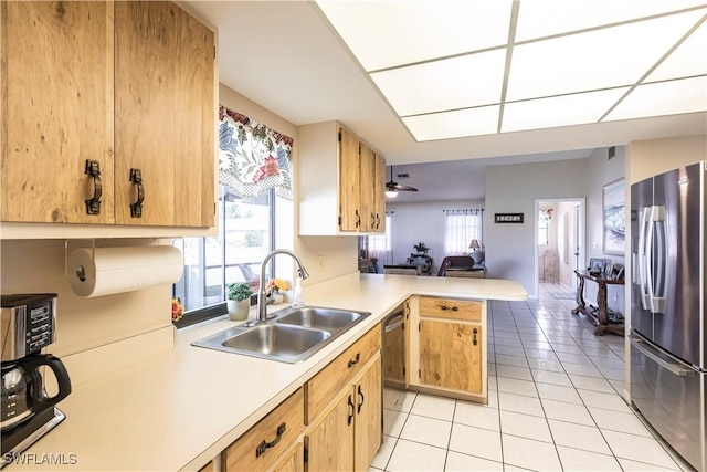 kitchen featuring stainless steel appliances, light countertops, open floor plan, a sink, and a peninsula