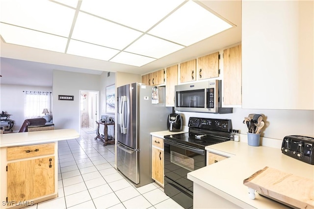 kitchen with light tile patterned floors, light countertops, appliances with stainless steel finishes, open floor plan, and a peninsula