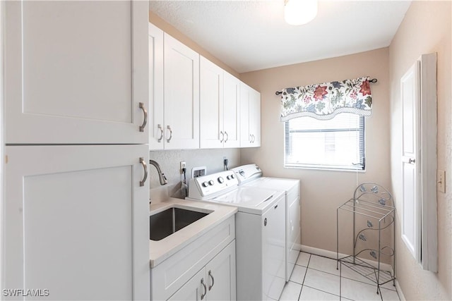 washroom featuring light tile patterned floors, cabinet space, washing machine and dryer, a sink, and baseboards