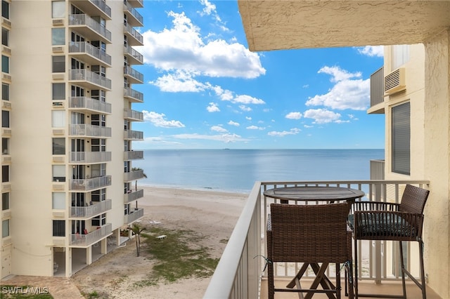 balcony featuring a view of the beach and a water view