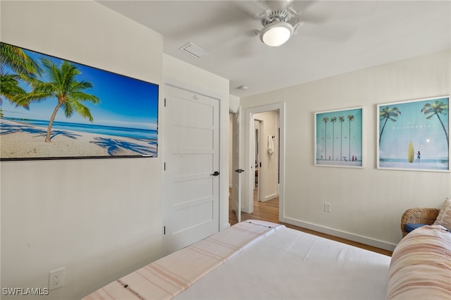 bedroom featuring a ceiling fan, visible vents, baseboards, and wood finished floors