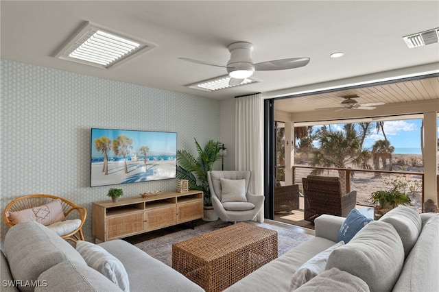 living room with a ceiling fan, visible vents, and wallpapered walls