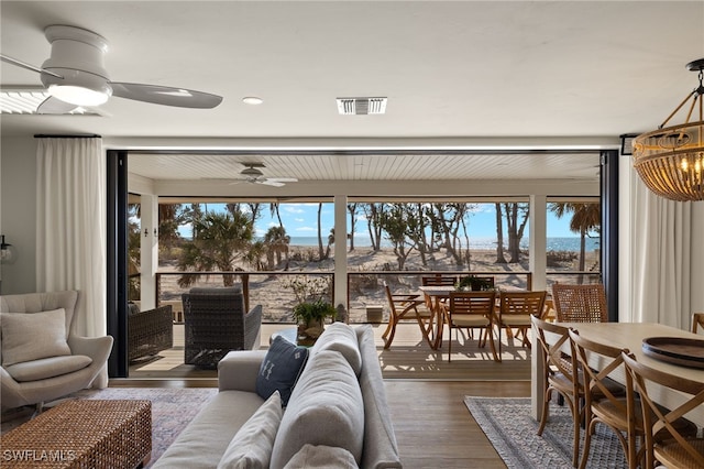 living room with plenty of natural light, visible vents, wood finished floors, and ceiling fan with notable chandelier