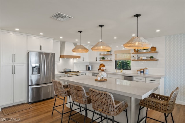 kitchen featuring visible vents, light countertops, appliances with stainless steel finishes, custom exhaust hood, and open shelves