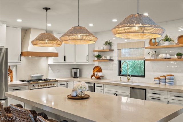 kitchen featuring custom range hood, stainless steel appliances, white cabinetry, pendant lighting, and a sink