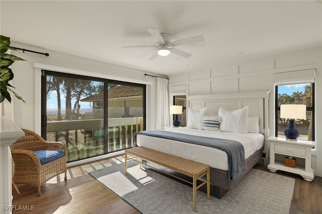 bedroom featuring access to exterior, ceiling fan, wood finished floors, and a decorative wall