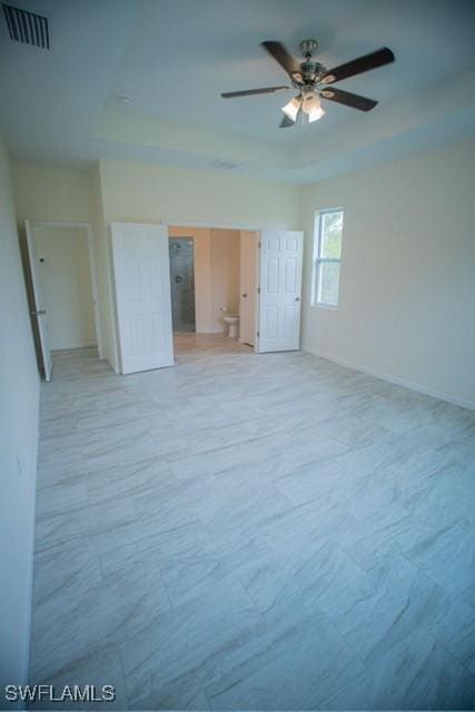 unfurnished room featuring a tray ceiling, visible vents, ceiling fan, and baseboards