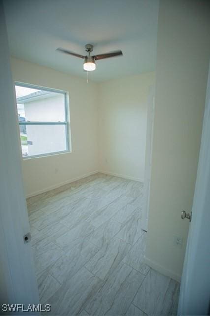 unfurnished room featuring a ceiling fan and baseboards