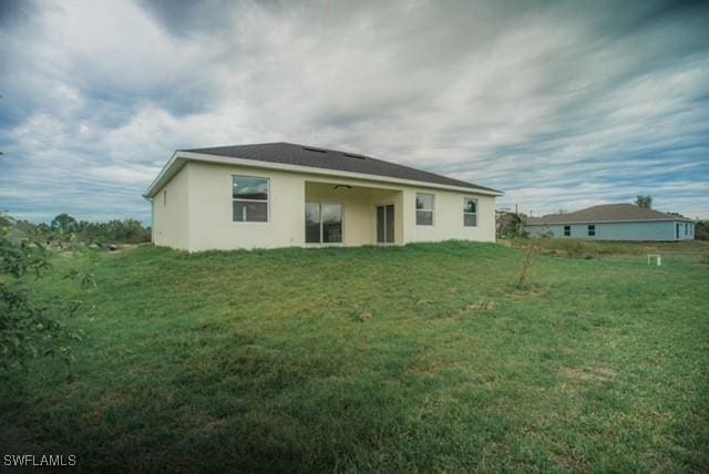 rear view of house featuring ceiling fan and a yard