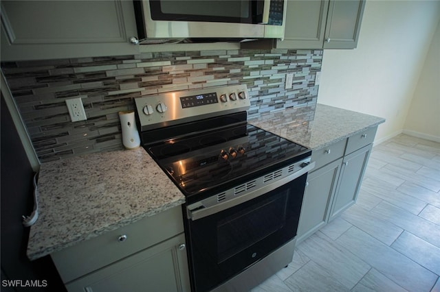 kitchen featuring light stone countertops, tasteful backsplash, baseboards, and stainless steel appliances