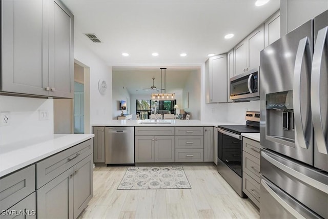 kitchen featuring visible vents, stainless steel appliances, light countertops, pendant lighting, and a sink