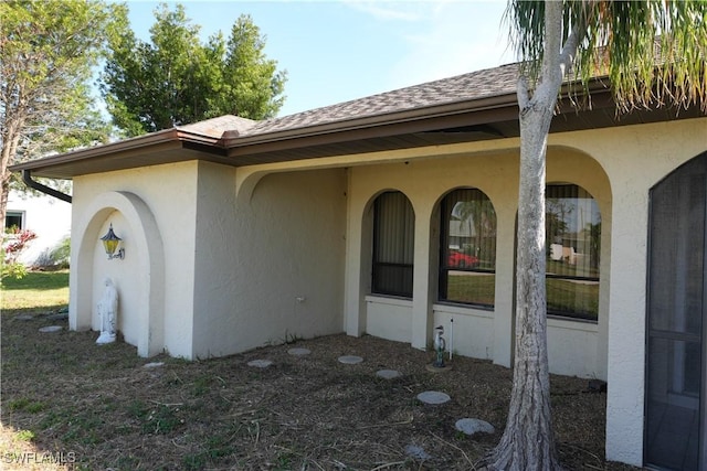 view of side of home featuring roof with shingles and stucco siding