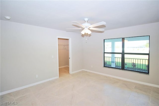 empty room with ceiling fan and baseboards