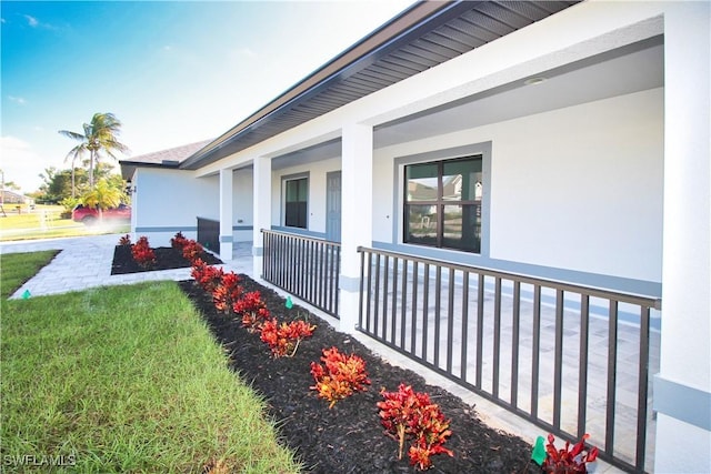 view of property exterior with a yard, a porch, and stucco siding