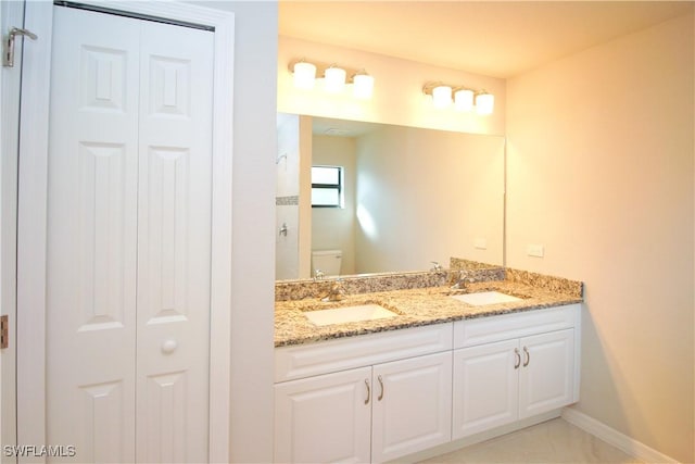 bathroom with a closet, a sink, toilet, and double vanity