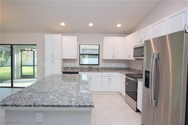 kitchen with stainless steel appliances, white cabinetry, a kitchen island, and light stone counters