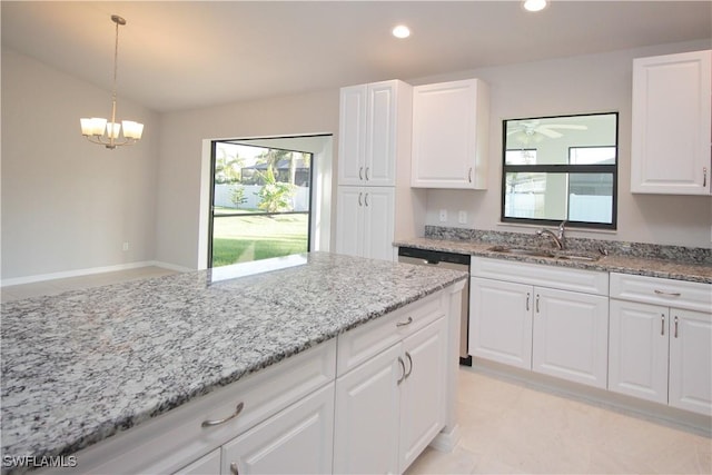 kitchen featuring decorative light fixtures, white cabinets, a sink, light stone countertops, and dishwasher