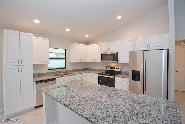 kitchen with appliances with stainless steel finishes, white cabinets, a sink, and light stone counters